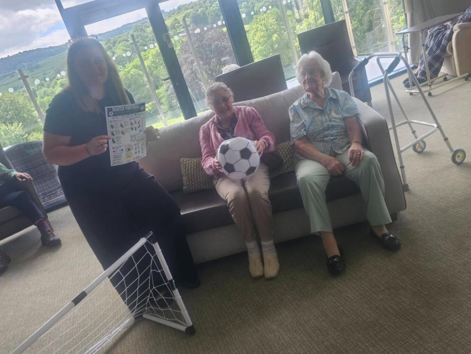 carer and residents seated football