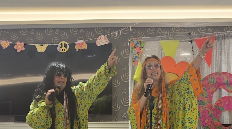 2 singers in 60s themed outfits singing for residents