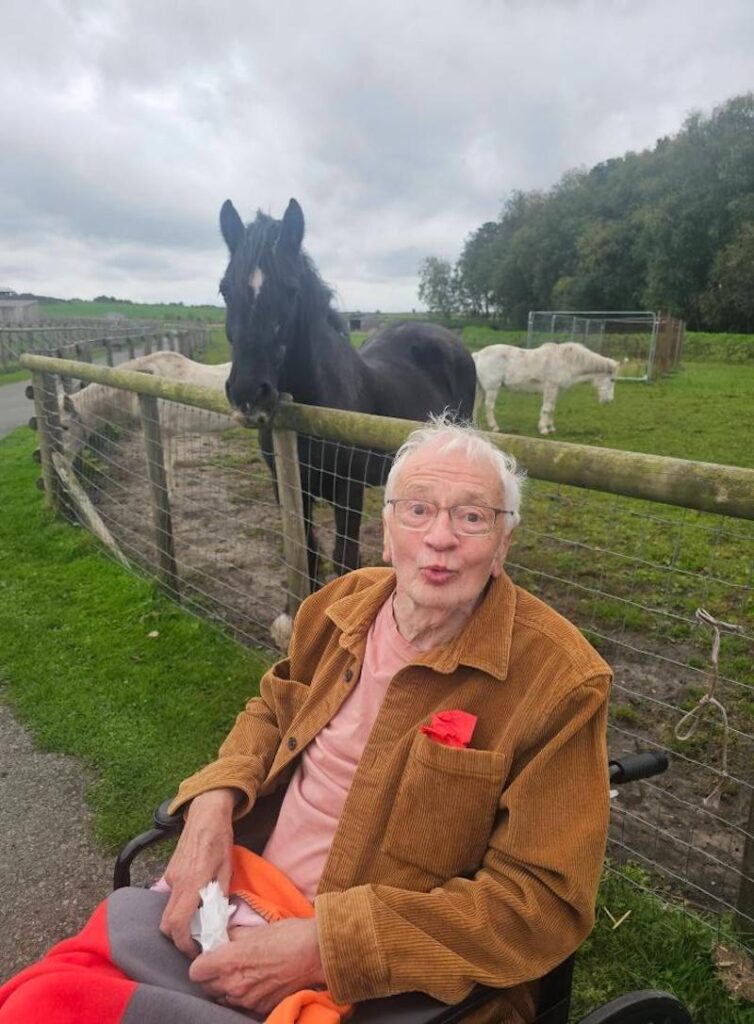 male resident wearing a brown jacket at the farm posing with a horse
