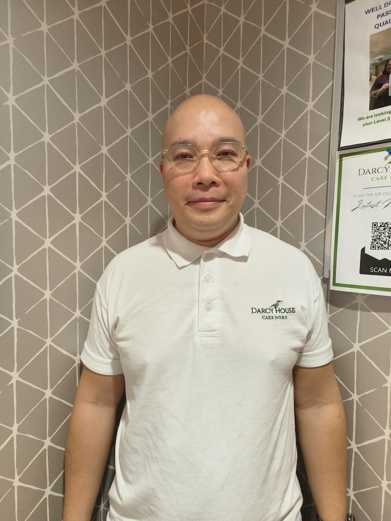 bald man wearing a white shirt having a headshot taken for the team page