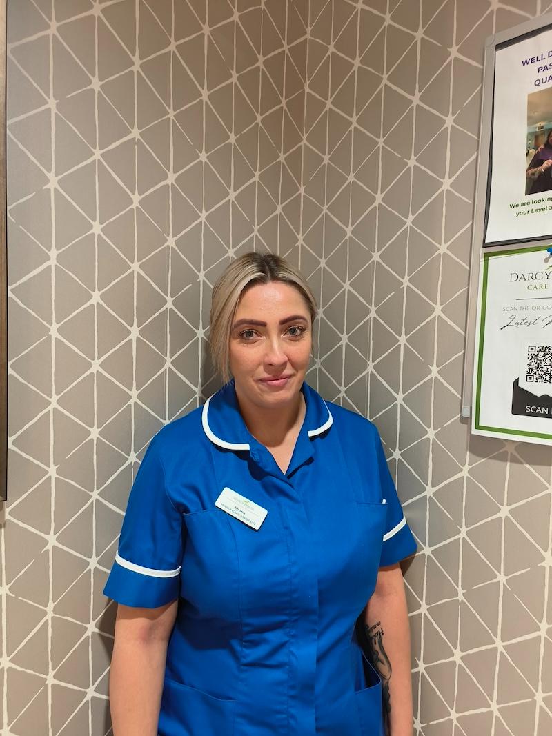 woman with blonde hair wearing a nurses uniform having a headshot taken for the team page