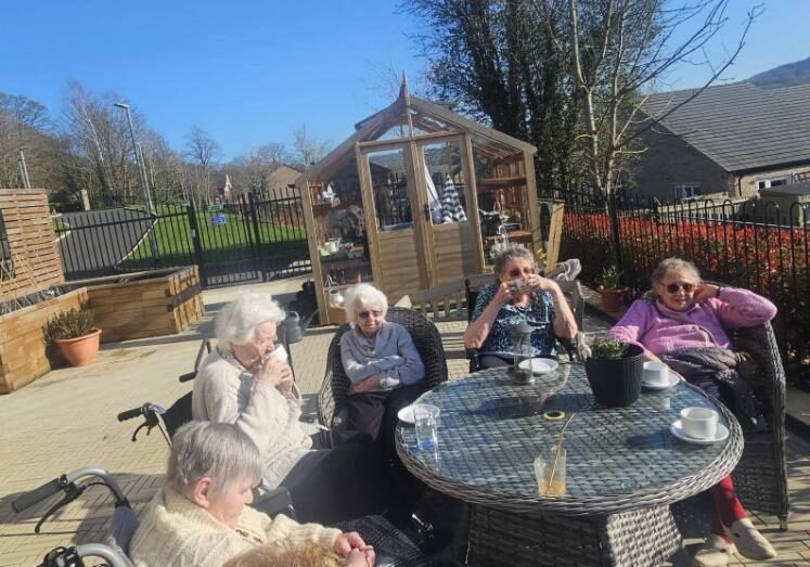 older ladies sat around a table out in a garden