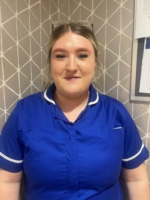 lady in a blue care uniform posing for a staff photo