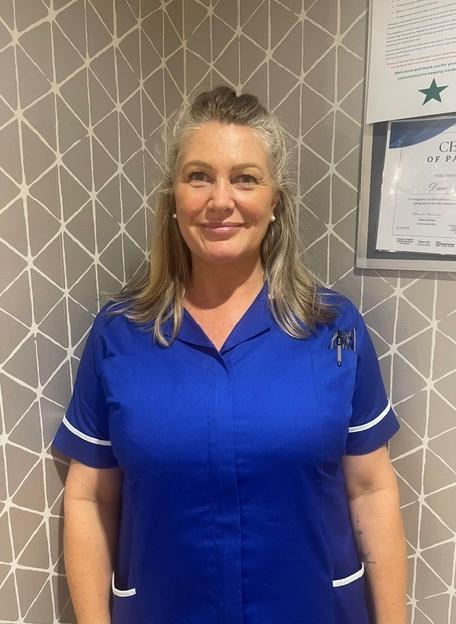 lady in a blue care uniform posing for a staff photo