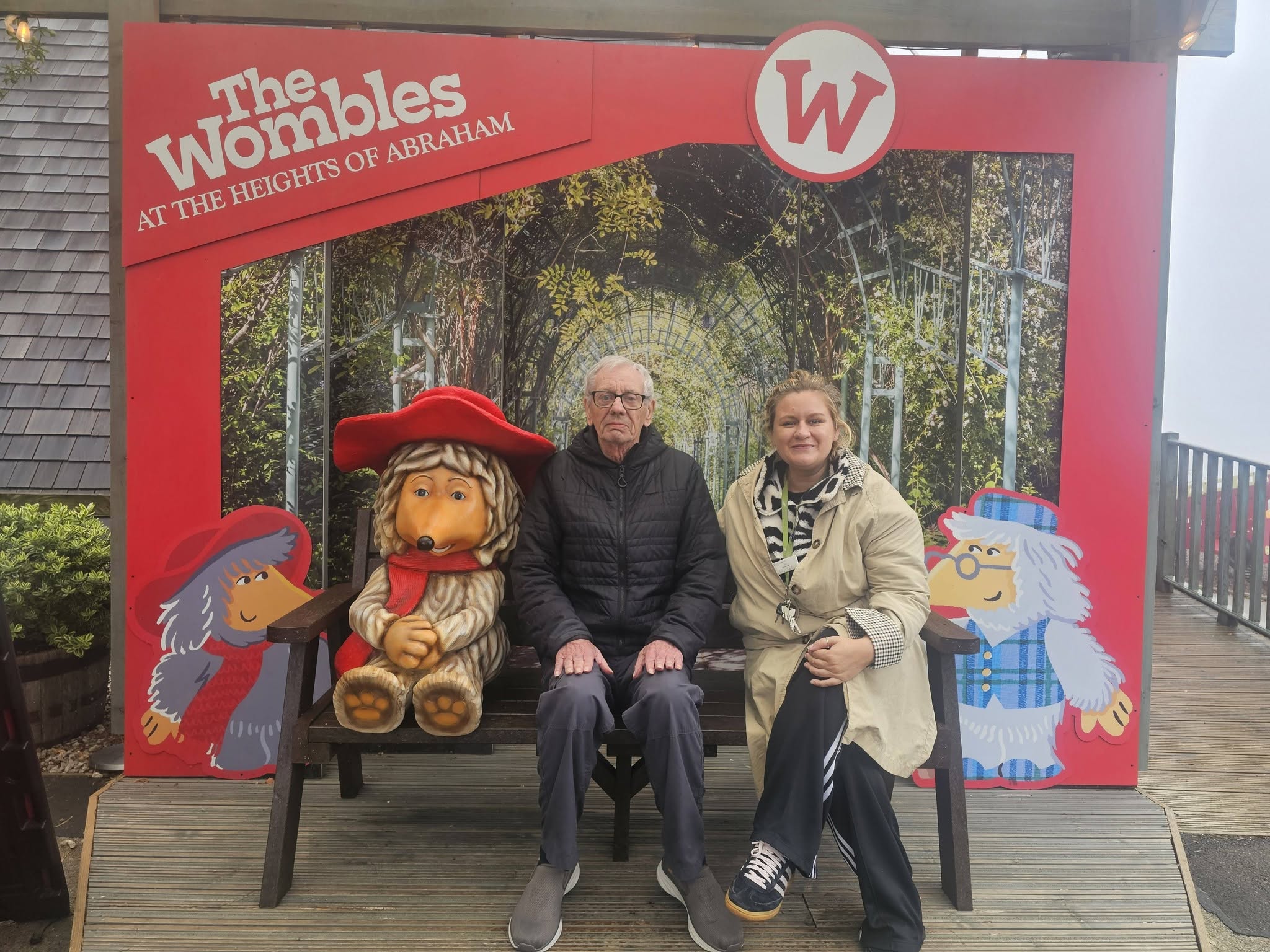 resident and carer sitting with the wombles sign